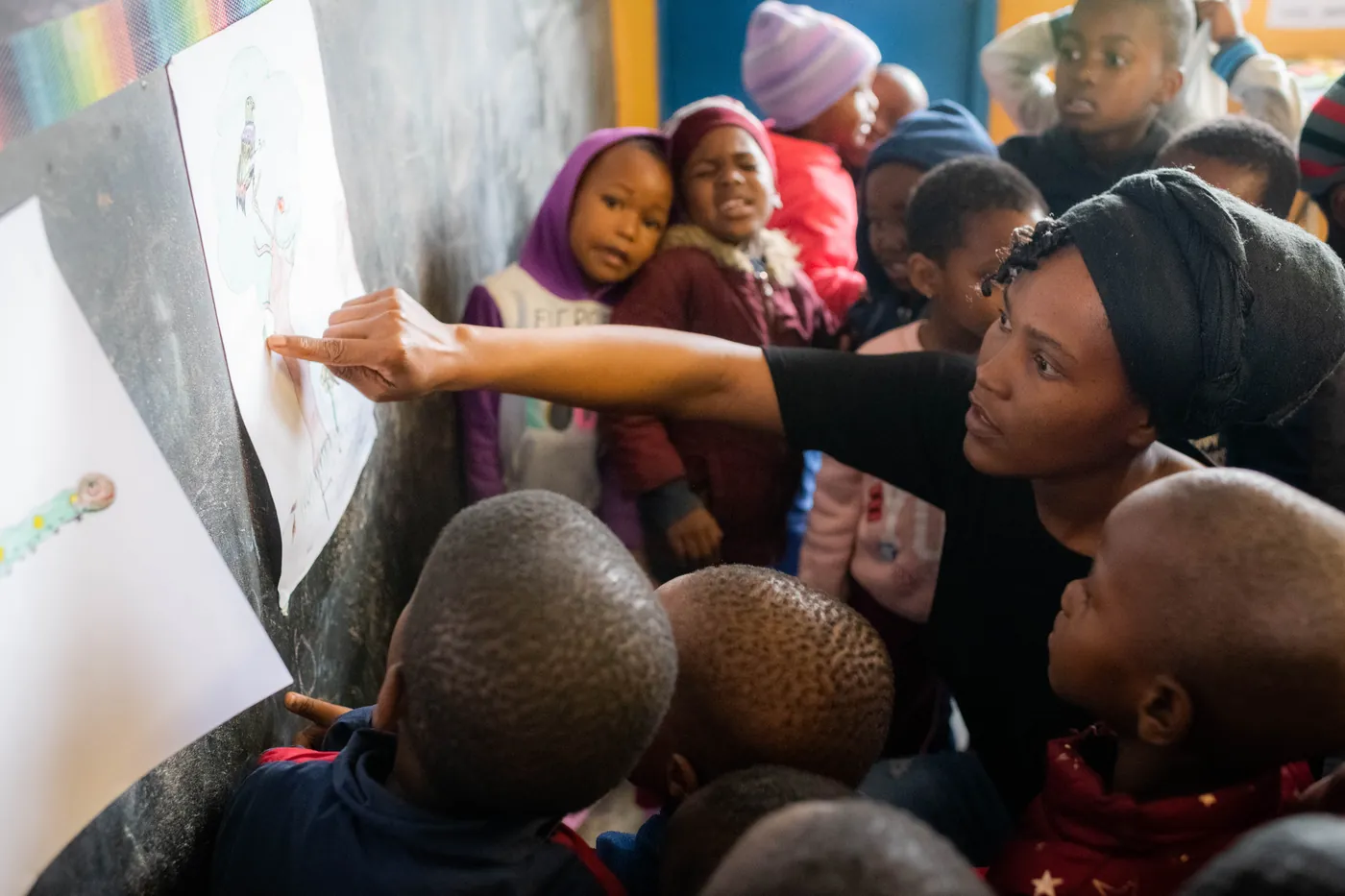 A Siyabonga teacher pointing to pictures on the board as children follow along