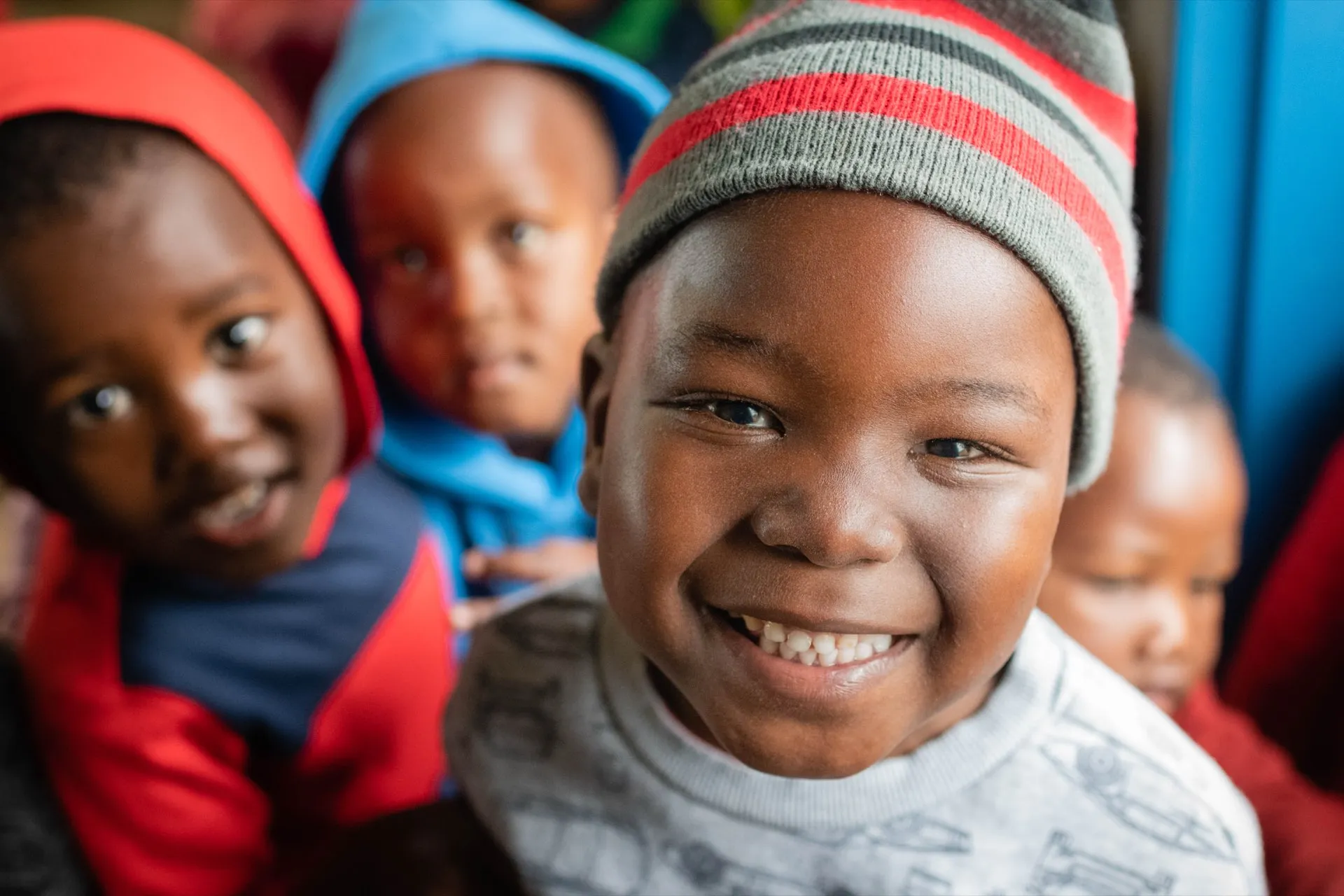 A young boy smiling in a brightly knitted beanie
