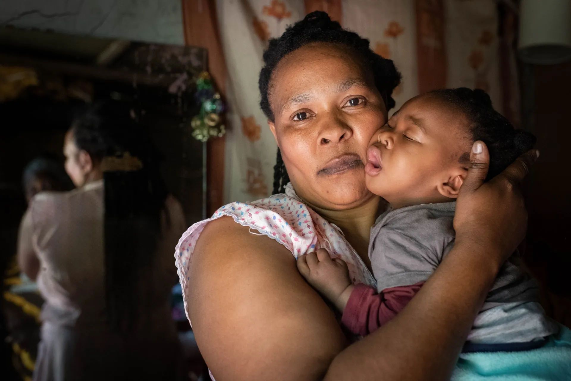 A mother holding her sleeping child at home