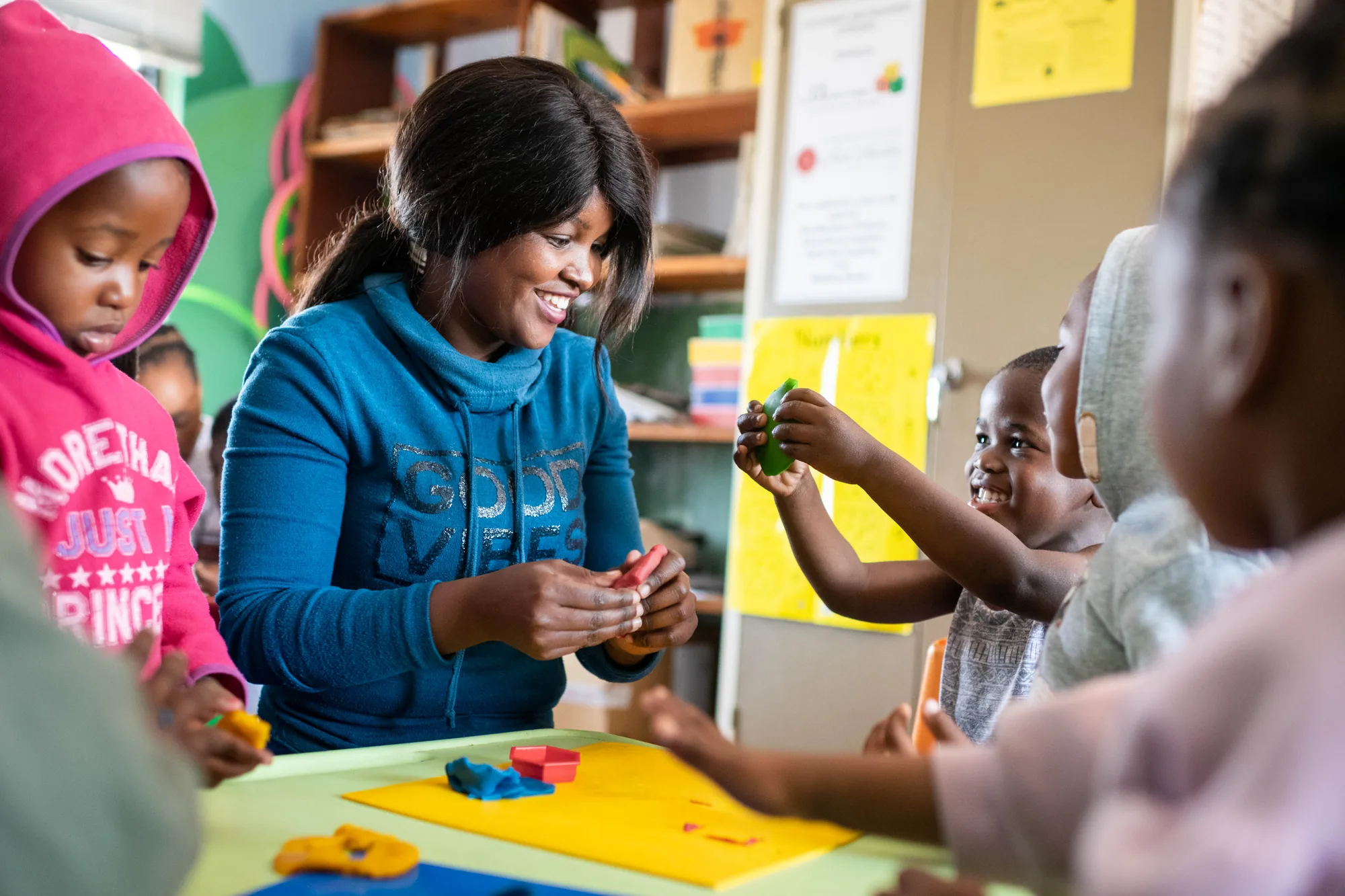 A Siyakwazi practitioner laughing with children as they play with modelling clay