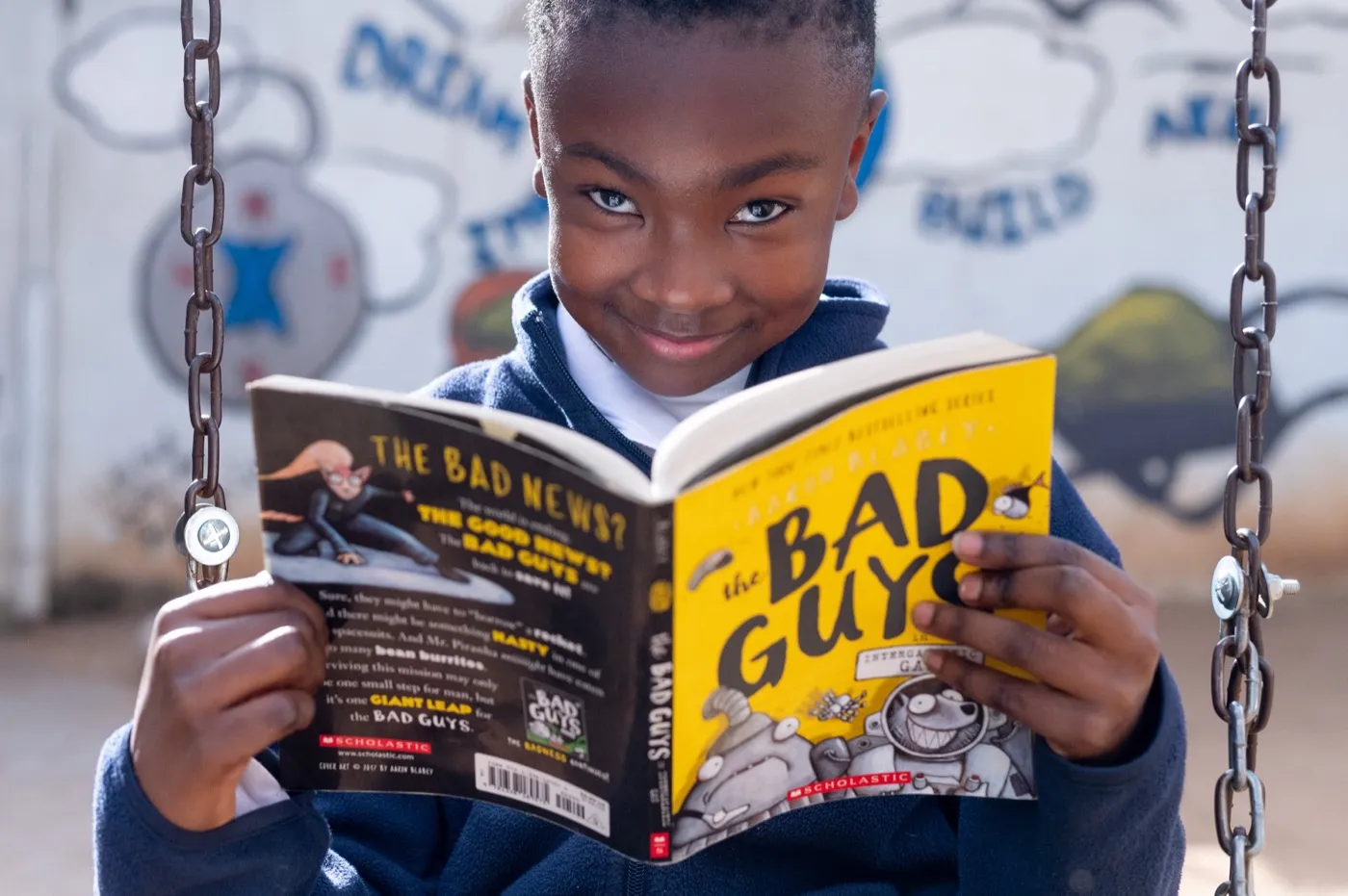 A girl smiling over an open book at Kgololo Academy