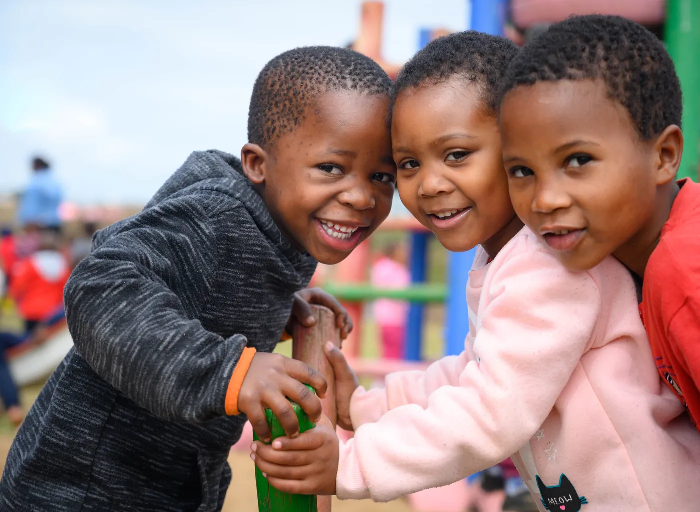 Three Siyabonga children hugging on the playground