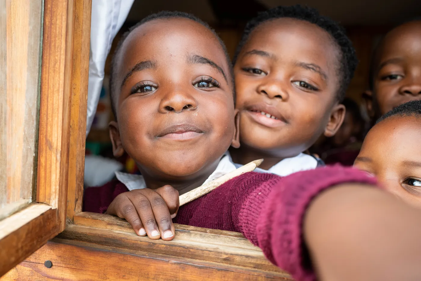Two boys grinning through a classroom window at a Siyakwazi centre