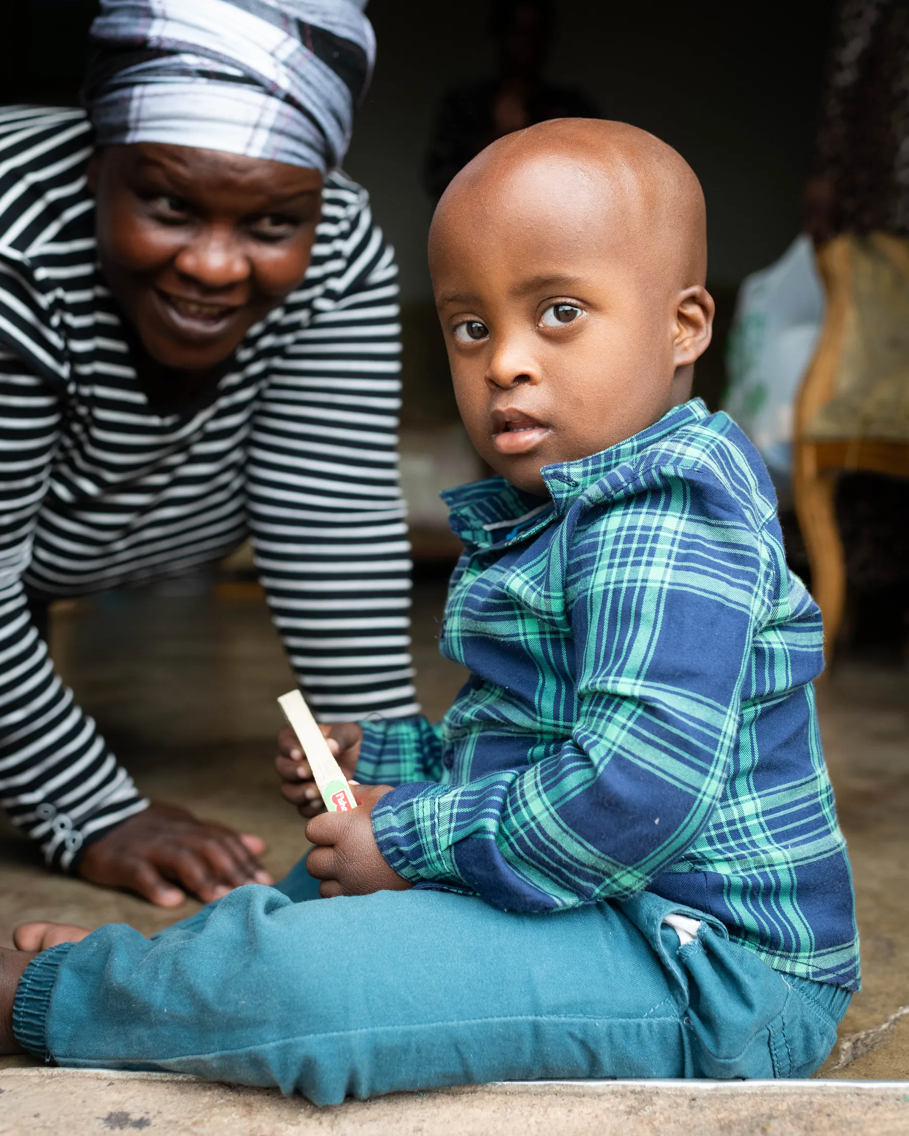 A Siyakwazi caregiver and a young boy playing together at home