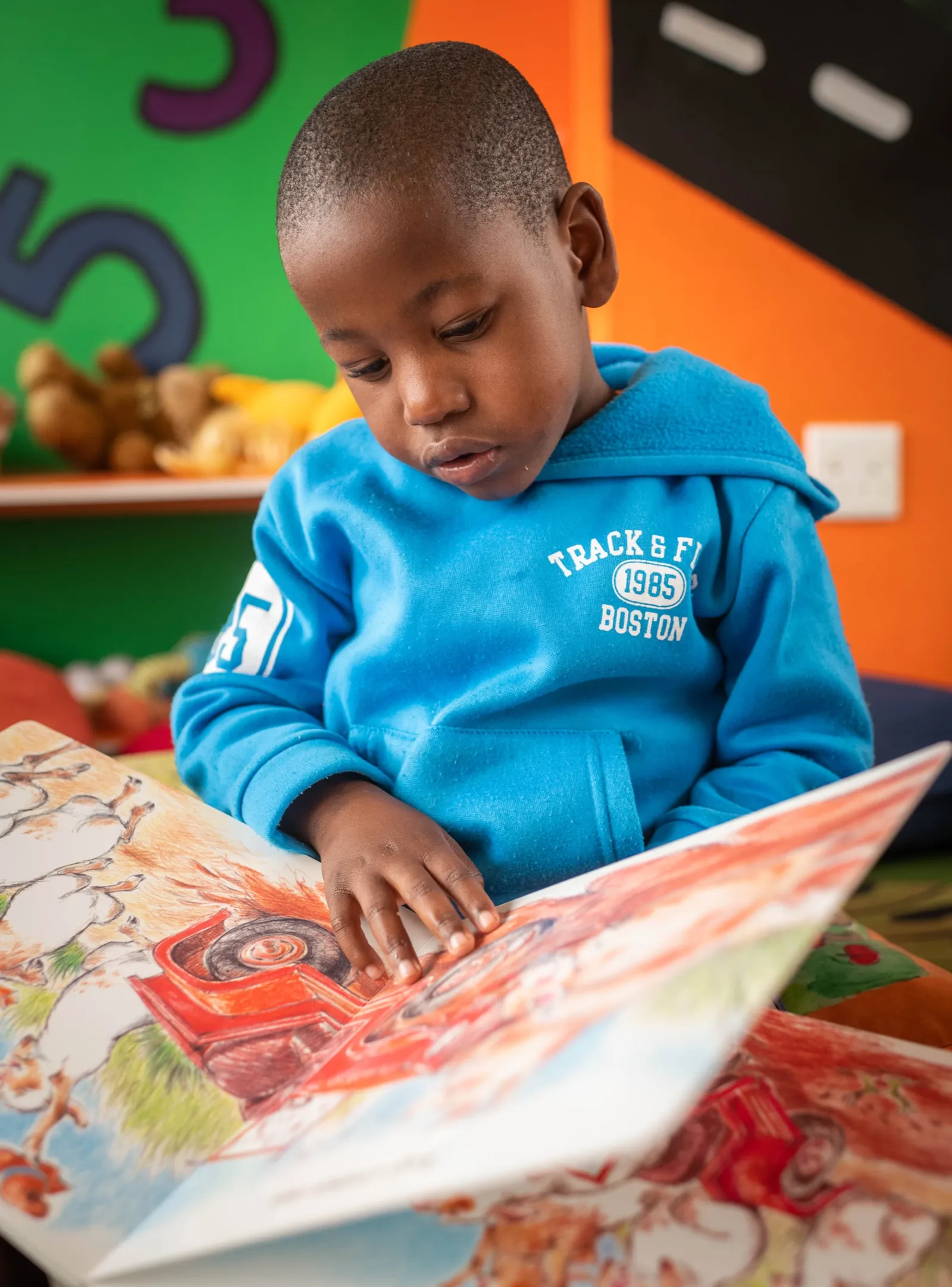 A child reading a picture book at a Thanda early learning centre